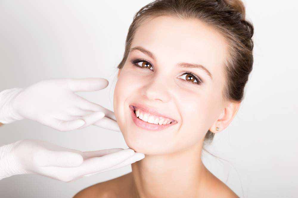 beautician hand's examining beautiful young female face