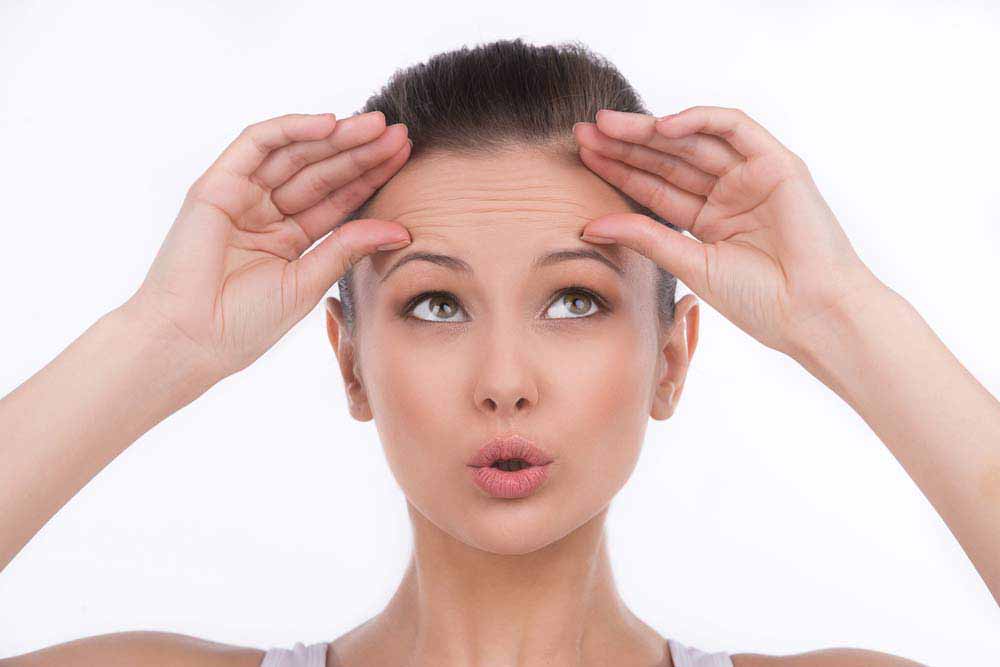 Surprised young woman touching her forehead and looking up