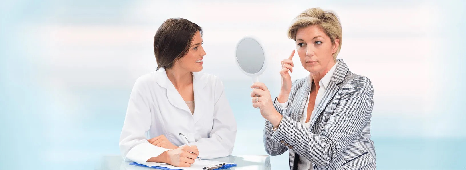 Woman pointing to spot on face, sitting next to a doctor