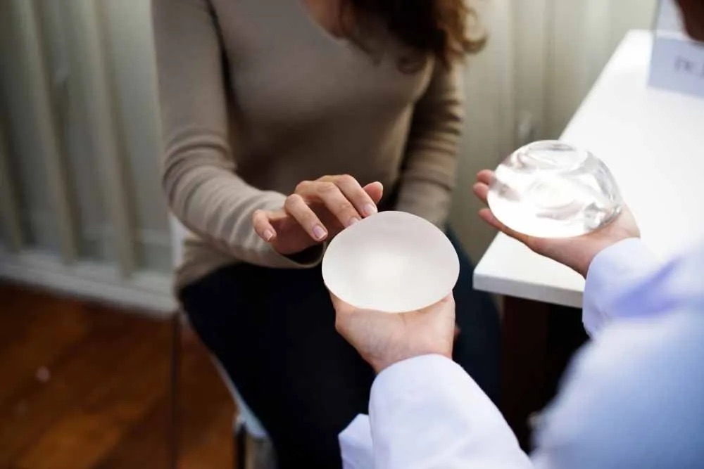 Doctor showing woman breast implant sizes